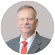 Man in a suit with a red tie smiling at the camera.