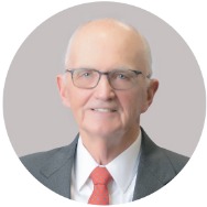 Man in a suit with a red tie smiling at the camera.