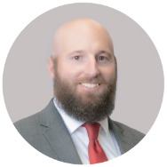 Man in a suit with a red tie smiling at the camera.