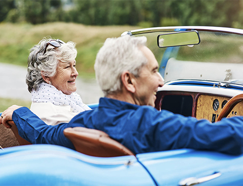 Mature couple drives in a vintage car.