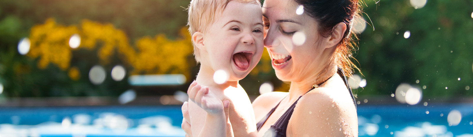 A mother enjoys holding her excited son while swimming.