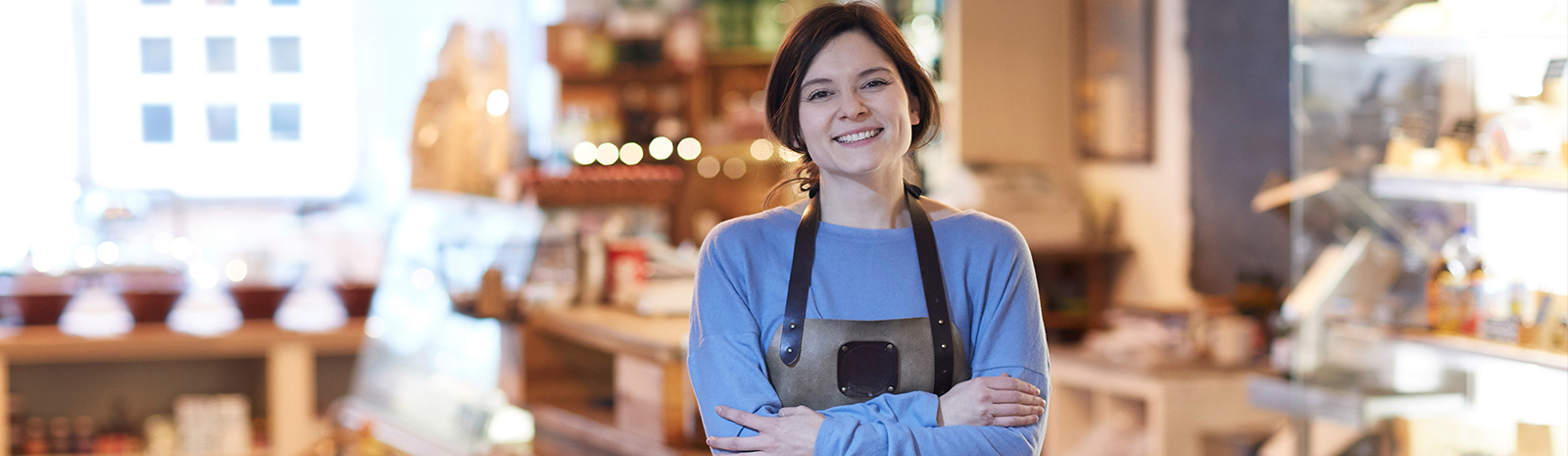 Female bake shop owner with arms crossed smiling.