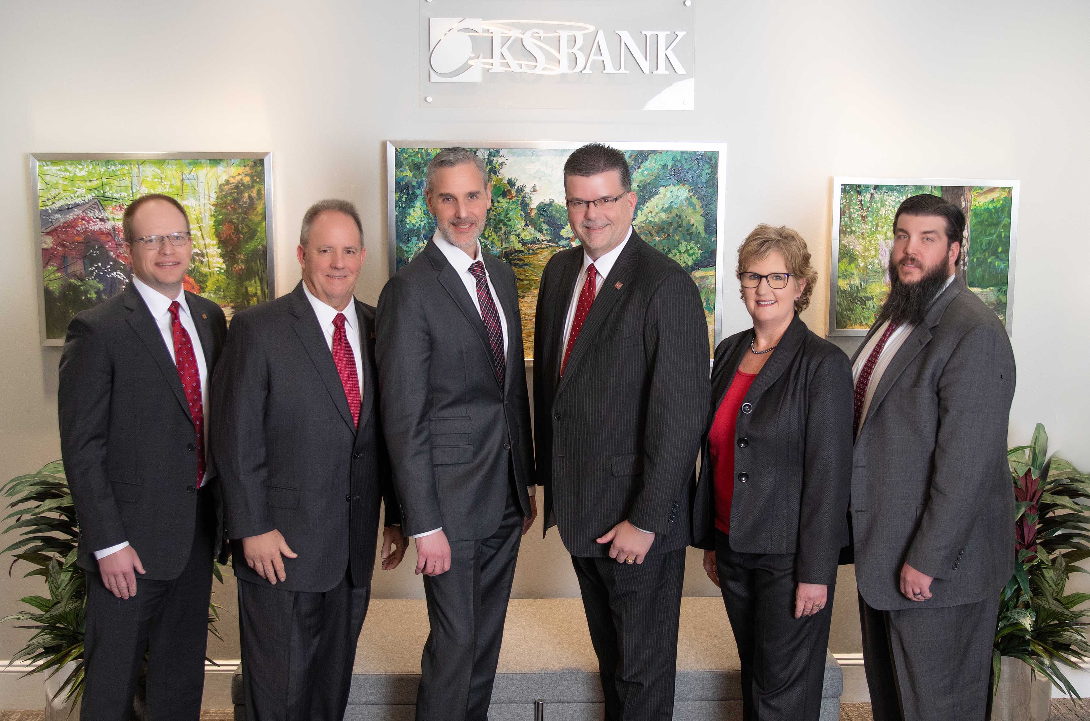 KS Bank executive team (5 men and 1 woman) standing in a line smiling at the camera.