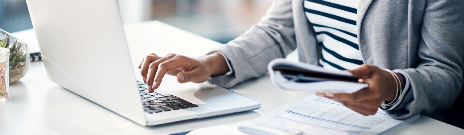hands typing on computer and looking at paperwork