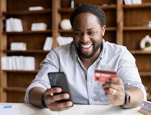Happy man holds cell phone and debit card.